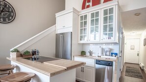 A modern kitchen with white cabinetry, stainless steel appliances, and a wooden island with bar stools.