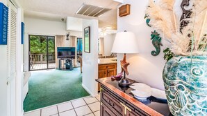 A hotel room with a green carpet, a TV, a dining area, and decorative seahorse wall art. - Heron Marsh 86 in Litchfield By the Sea, steps away from the pool and beach (Pawleys Island)