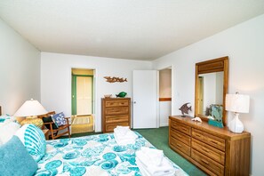 Un dormitorio con cama, cómoda, espejo y puerta que da a otra habitación.
