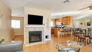 Una sala de estar moderna con chimenea, televisor de pantalla plana y mesa de centro de vidrio.