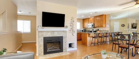 A modern living room with a fireplace, a flat-screen TV, and a glass coffee table.