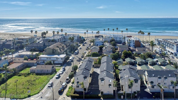 Zona residencial costera con casas, playa y palmeras.