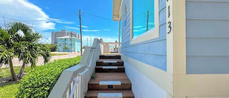 Un escalier en bois mène à un bâtiment sur lequel on peut voir le numéro « 213 » sur le côté.