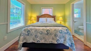 A bedroom with a bed, two bedside lamps, a ceiling fan, and a window with blinds. - 213 Ohio Cozy Cottage Just Short Walk to Beach (Fort Myers Beach)
