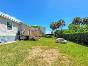 A residential property with a deck, outdoor seating, and a well-maintained lawn. - 213 Ohio Cozy Cottage Just Short Walk to Beach (Fort Myers Beach)
