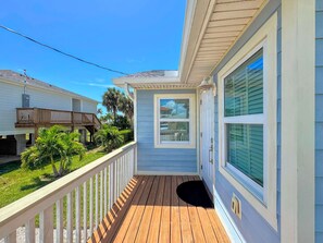 A wooden deck with a white railing, a door with a window, and a view of neighboring houses. - 213 Ohio Cozy Cottage Just Short Walk to Beach (Fort Myers Beach)