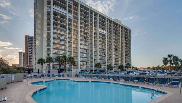 Un hotel de gran altura con piscina, varios balcones y un área de estacionamiento.