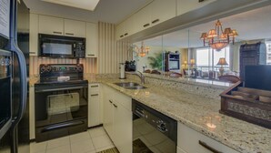 Una cocina moderna con encimera de granito, electrodomésticos de acero inoxidable y un amplio ventanal con vistas a la ciudad.