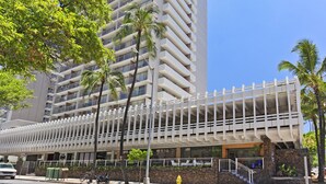 Um hotel moderno com estrutura em vários andares, uma passarela coberta para pedestres e fachada de pedra.
