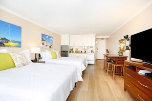 A hotel room with two beds, a kitchenette, a dining area, and a TV.