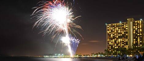 A beachfront hotel with a view of fireworks over the water.