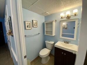 A bathroom with a toilet, sink, and framed pictures on the wall.
