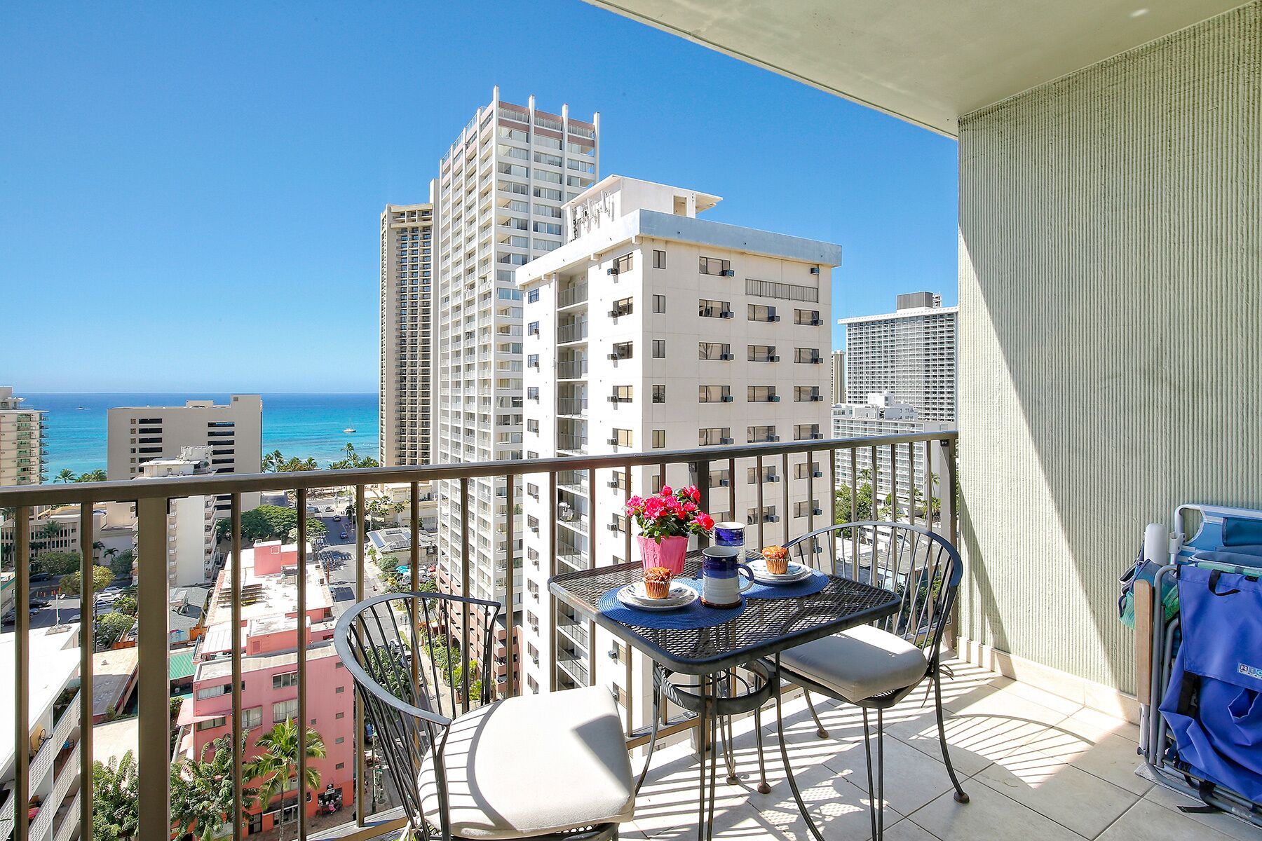 A balcony with a table, chairs, and a potted plant.