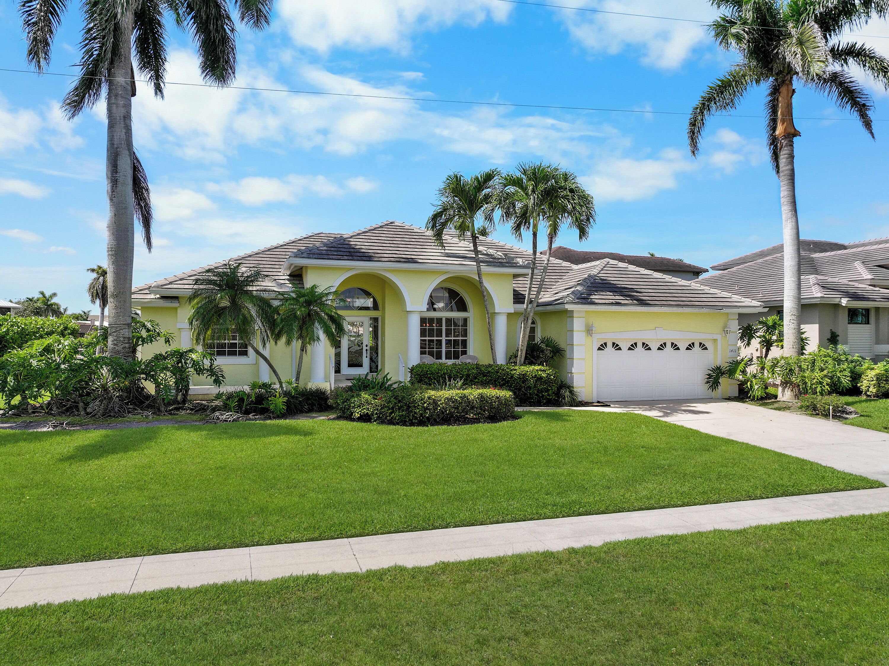 A yellow house with a tiled roof, arched windows, and a garage.
