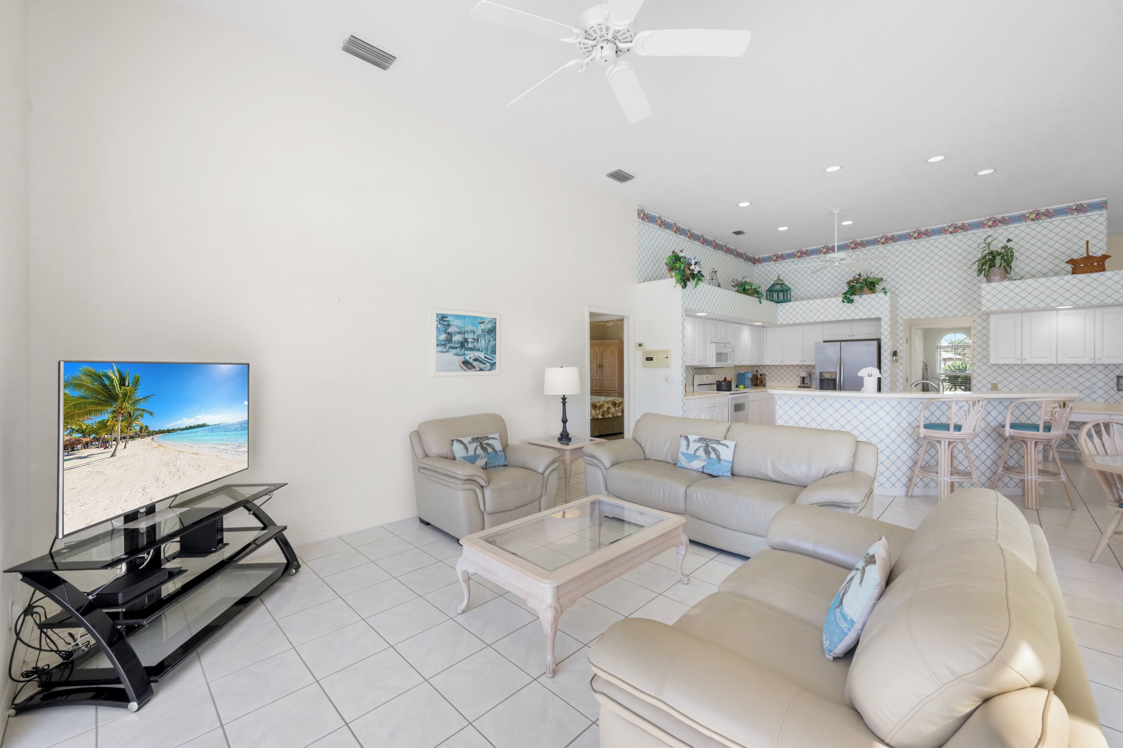 A modern living room with a flat-screen TV, a glass coffee table, and a beige sofa.