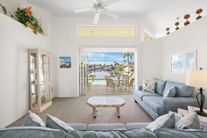 Un salon spacieux comprenant un meuble vitré, un canapé, une table basse et donnant sur une piscine et un espace extérieur.
