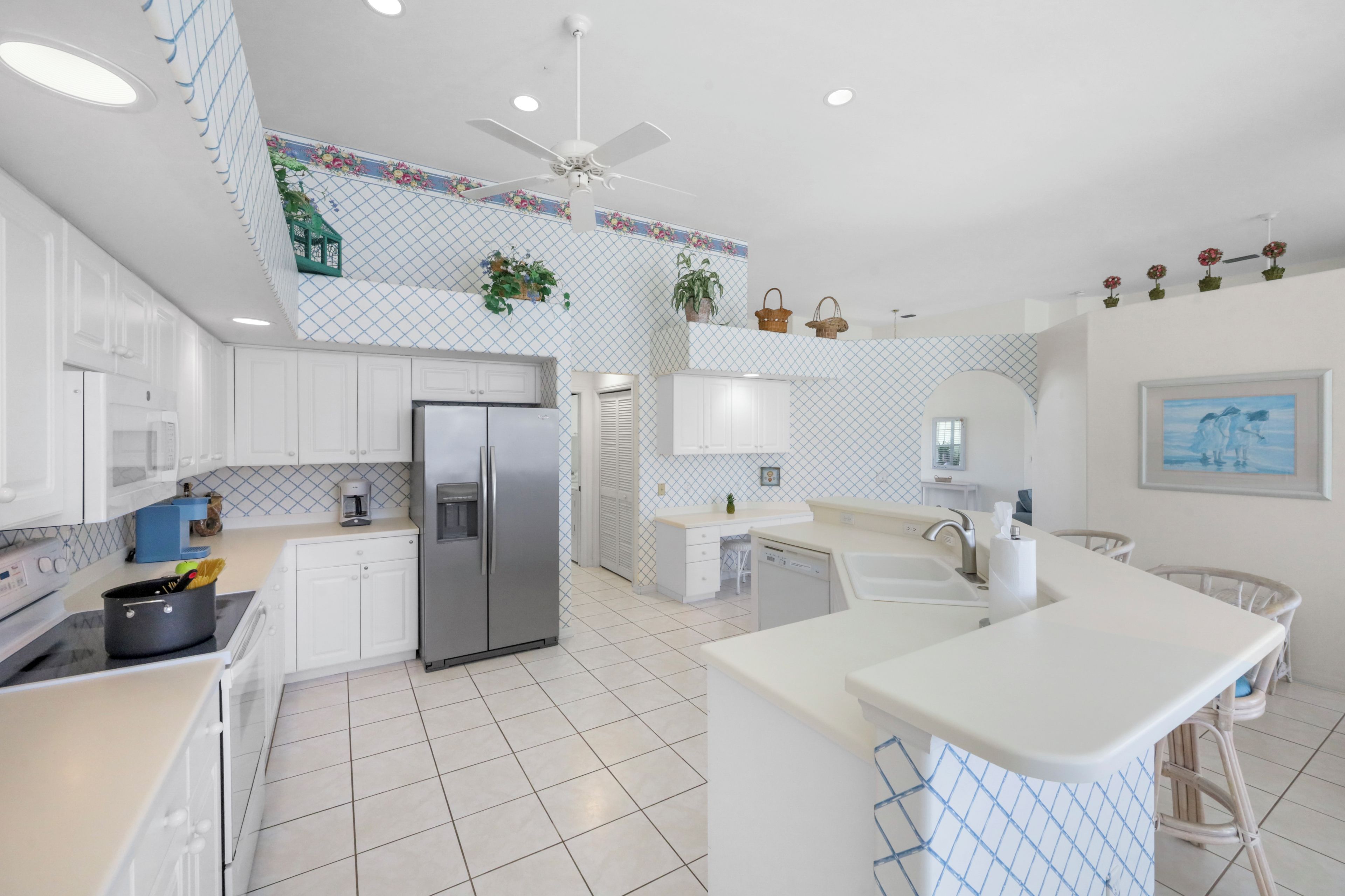 A modern kitchen with white cabinetry, a central island, and a ceiling fan.