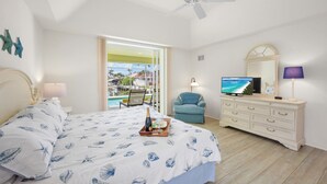 Een slaapkamer met een bed, een dressoir, een televisie, een stoel en uitzicht op de omgeving.