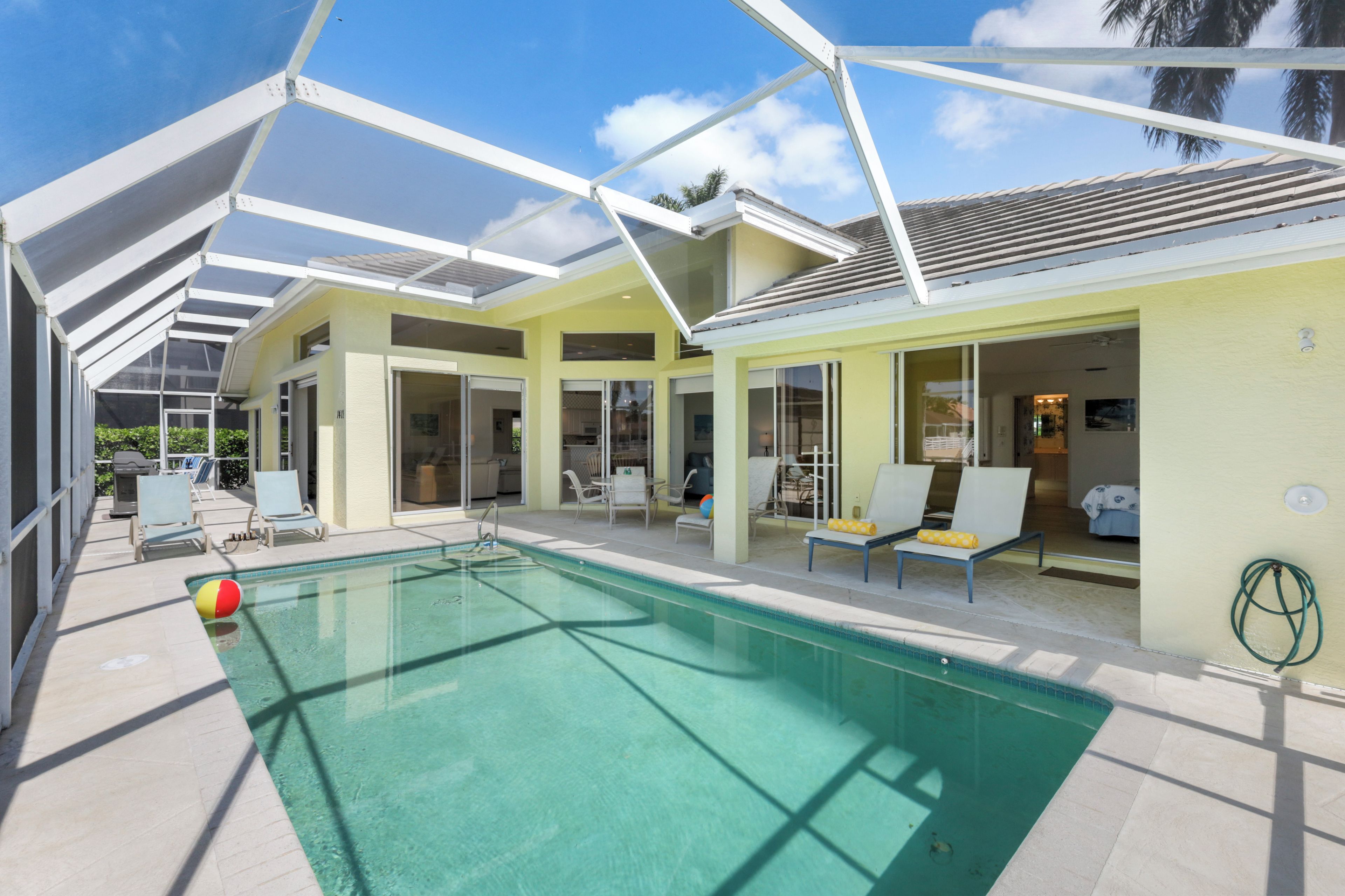 A swimming pool with lounge chairs and a covered patio area.