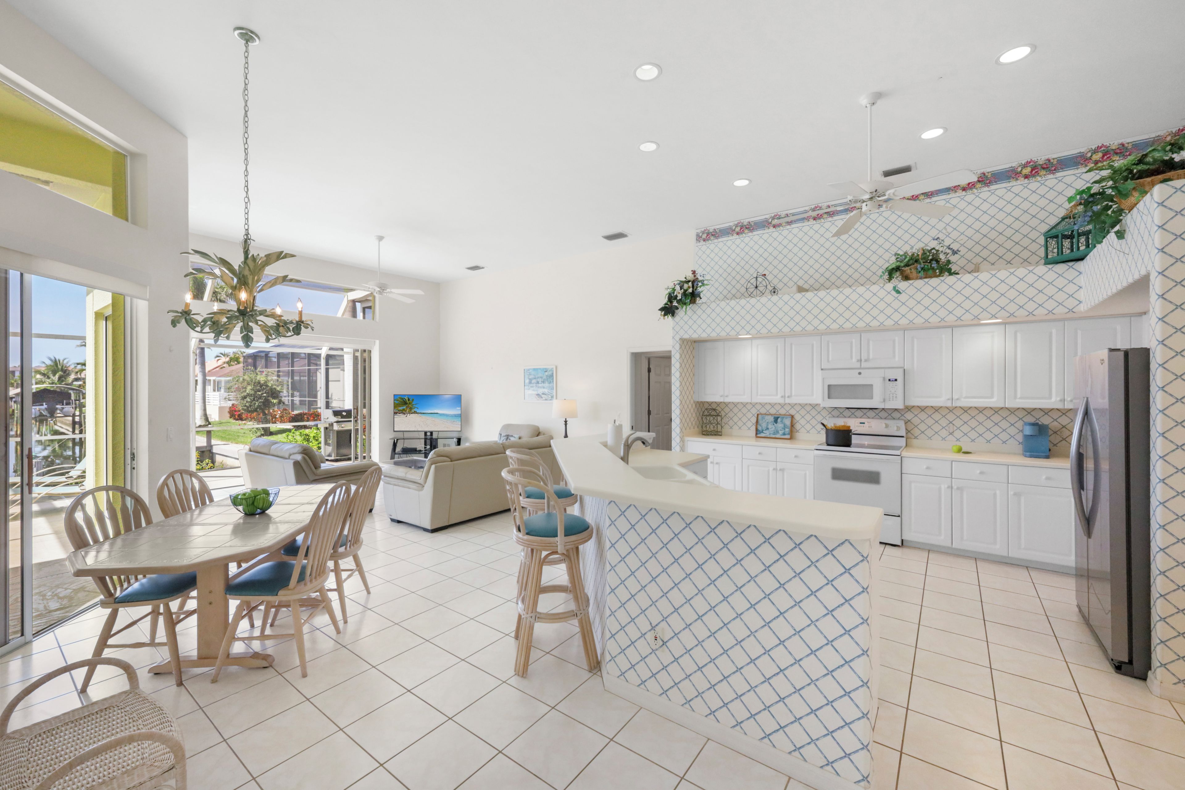 A modern kitchen with white cabinets, a large island, and a dining area with a table and chairs.
