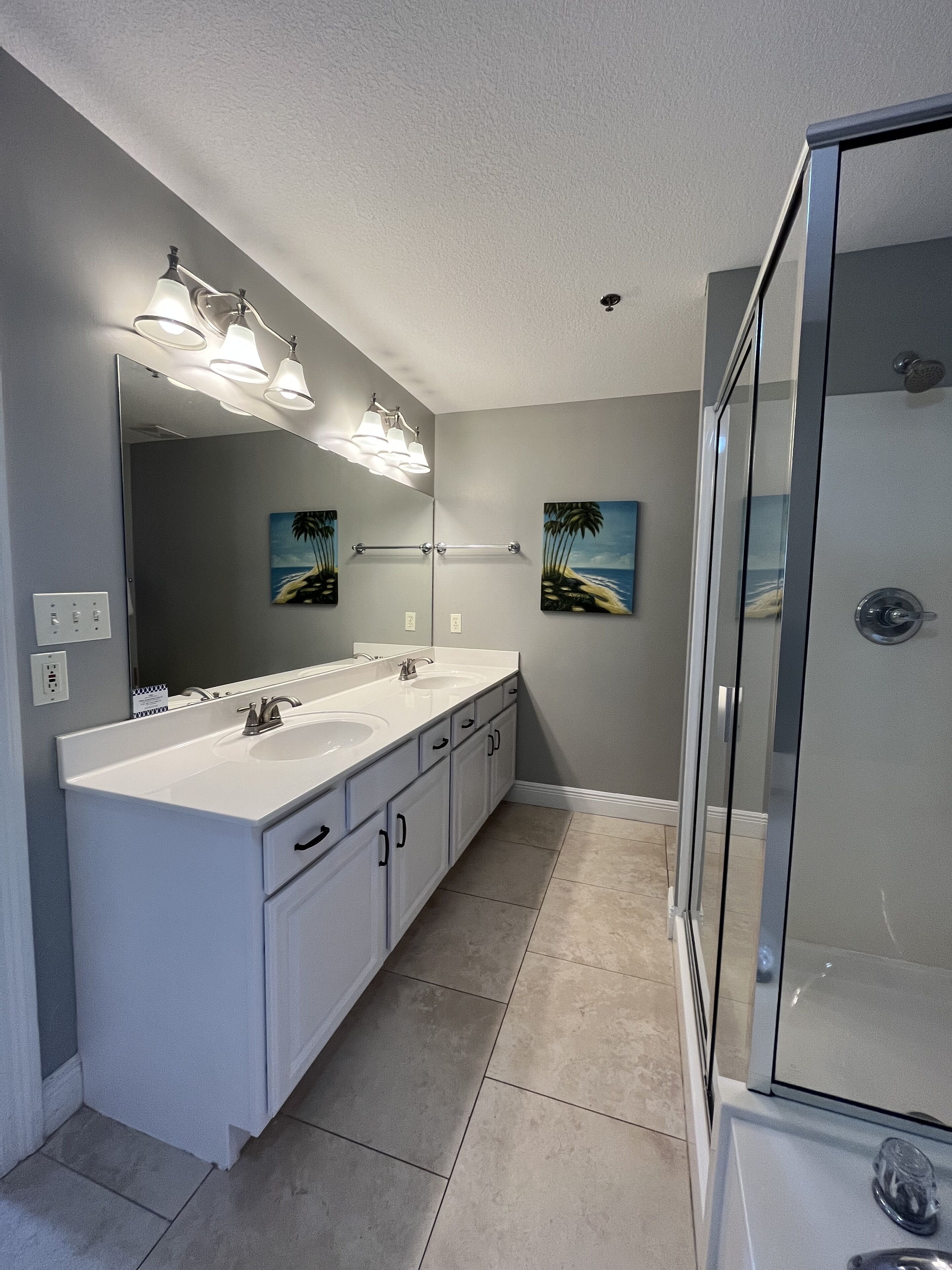 Un baño moderno con tocador doble, un espejo grande y cabina de ducha de vidrio.