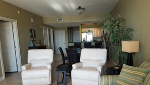 Una sala de estar con dos sillones blancos, un sofá a rayas, una mesa de centro y un comedor con una mesa y sillas.