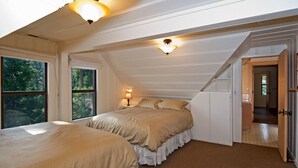 Un dormitorio con dos camas, una lámpara en el techo y vistas al exterior.