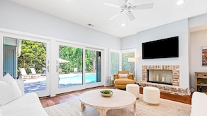 A modern living room with a fireplace, a round coffee table, and a large TV mounted on the wall.