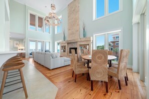 A spacious living area with a fireplace, a dining table with chairs, a sofa, and a kitchen counter with stools.