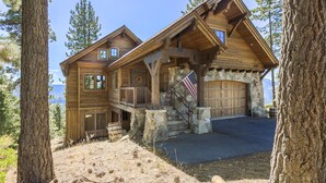 A large log cabin with a stone foundation, multiple windows, and a garage. - Overlook Lake View Lodge by Tahoe Getaways- Dog Friendly, HOA, Donner Lake Views + Hot Tub (Truckee)