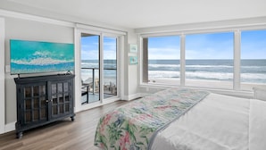 A bedroom with a large bed, a TV, and a view of the ocean. - Beachfront ~ Private Balcony ~ Recent Updates (Miramar Beach)