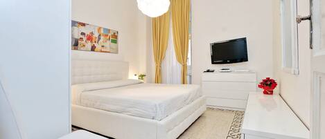 A modern bedroom with a bed, a desk, a TV, and a painting on the wall.