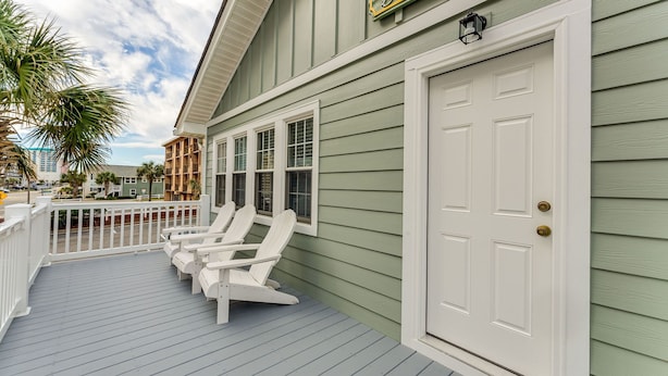 A wooden deck with white Adirondack chairs, a white door, and a green building facade. - 2 story, 2nd Row House w/private pool & hot tub + Free Attraction Tickets! (North Myrtle Beach)