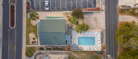Vista aérea de una propiedad con piscina, estacionamiento y un edificio con techo verde.