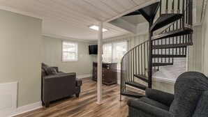 A modern living room with a dark gray sofa, a small table, and a staircase with black railings. - 2 story, 2nd Row House w/private pool & hot tub + Free Attraction Tickets! (North Myrtle Beach)
