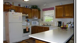 Una cocina con armarios de madera, un refrigerador blanco, un microondas y un lavamanos.