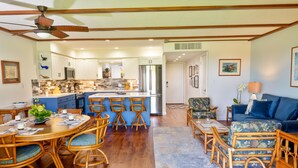 A spacious living area with a dining table, chairs, a sofa, and a kitchen in the background.