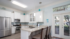 Una cocina moderna con armarios blancos, electrodomésticos de acero inoxidable y una isla grande con taburetes de bar.