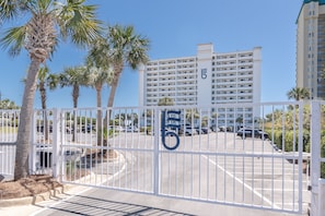 A gated parking area with a building in the background. - Breakers East 1105~ Spacious 2BR/2BA~beach setup- Covered Parking (Destin)