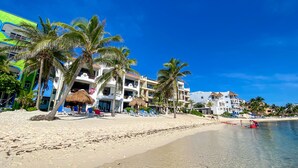 A beach resort with multiple-story buildings, palm trees, and a clear blue sky. - Spacious with beautiful upper level views of Half Moon Bay! (Akumal)