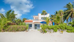 Ein Anwesen am Strand mit einem weißen Gebäude, einem roten Ziegeldach und einem Balkon.