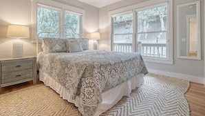 A bedroom with a large bed, two bedside lamps, a nightstand with drawers, and a ceiling fan. - Completely Renovated, 5 min walk to beach (Kiawah Island)