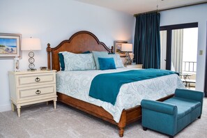 Une chambre à coucher avec un lit en bois, deux tables de chevet, une commode, une chaise et une vue sur l’extérieur.