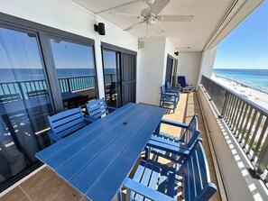 Un balcon avec une table et des chaises, un ventilateur de plafond et une vue sur la plage.