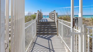A wooden boardwalk leading to a beach with a clear view of the ocean.