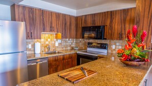 Eine moderne Küche mit Holzschränken, Granit Arbeitsplatten, Edelstahlgeräten und einer dekorativen Pflanzengestaltung.