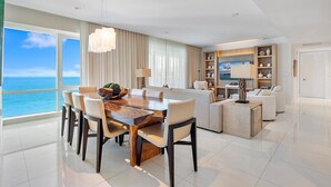 Een moderne woonkamer met een eethoek, grote ramen en uitzicht op de oceaan.