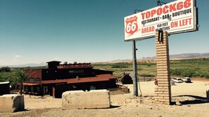 A Topock 66 restaurant and bar sign with a view of a building and landscape in the background.