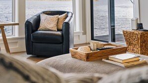 A cozy living room with a leather armchair, a wooden side table, and a cushioned sofa. - UNIQUE RESIDENTIAL OCEANFRONT PROPERTY ON VANCOUVER ISLAND  (Nanoose Bay)