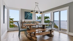 A dining area with a wooden table, benches, and chairs, overlooking a body of water. - UNIQUE RESIDENTIAL OCEANFRONT PROPERTY ON VANCOUVER ISLAND  (Nanoose Bay)